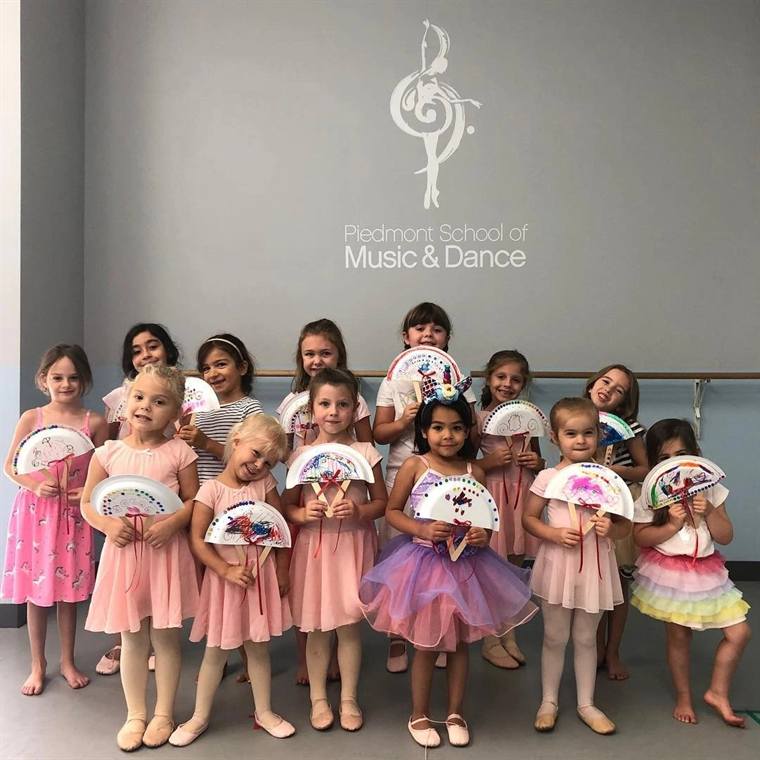 A group of young dancers posed together in front of the studio sign