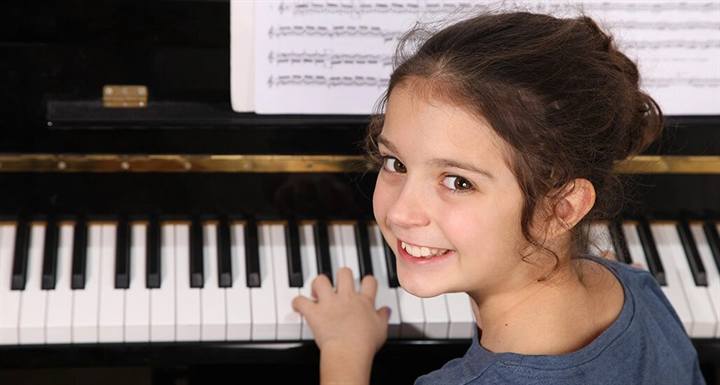 Young student smiling at a piano keyboard