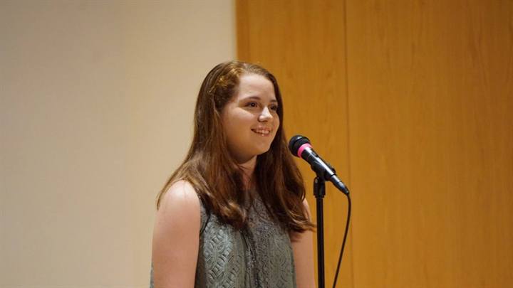 Student singing into a microphone on stage